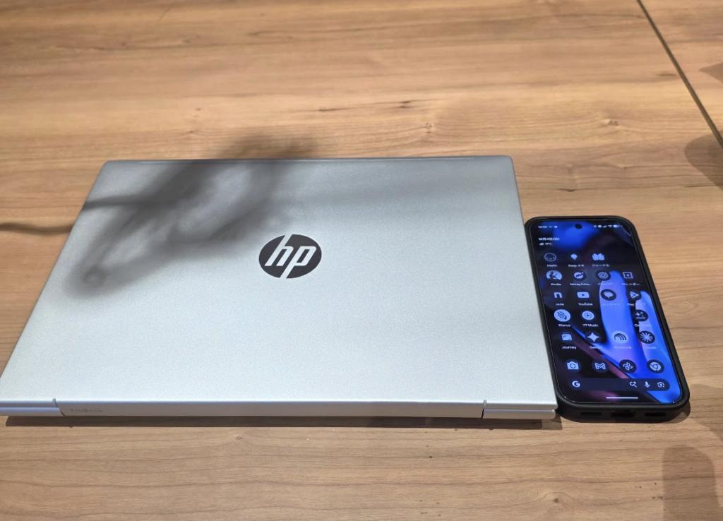 閉じたHP ProBook 4 G2a 14 AI PCとスマートフォンを並べた様子