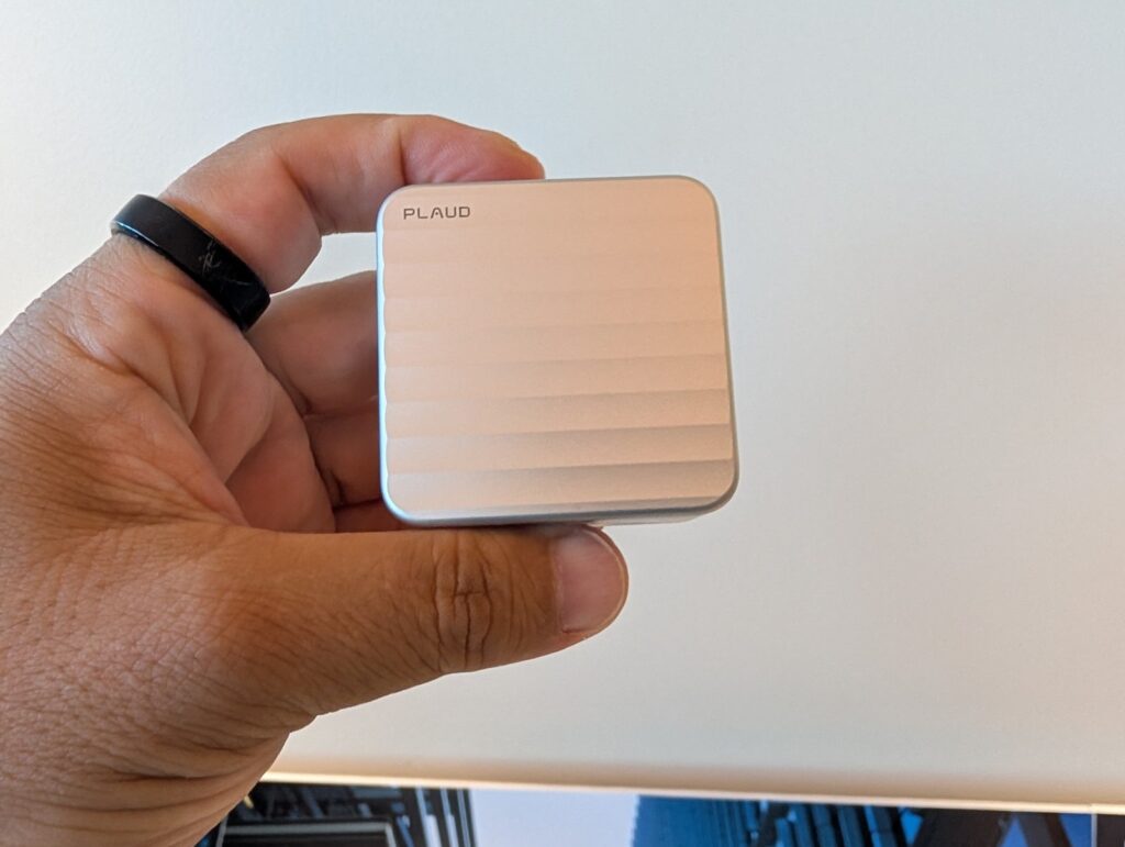 Plaud Oneの充電ケースを手に持った様子。天面にPLAUDロゴと波状のテクスチャ